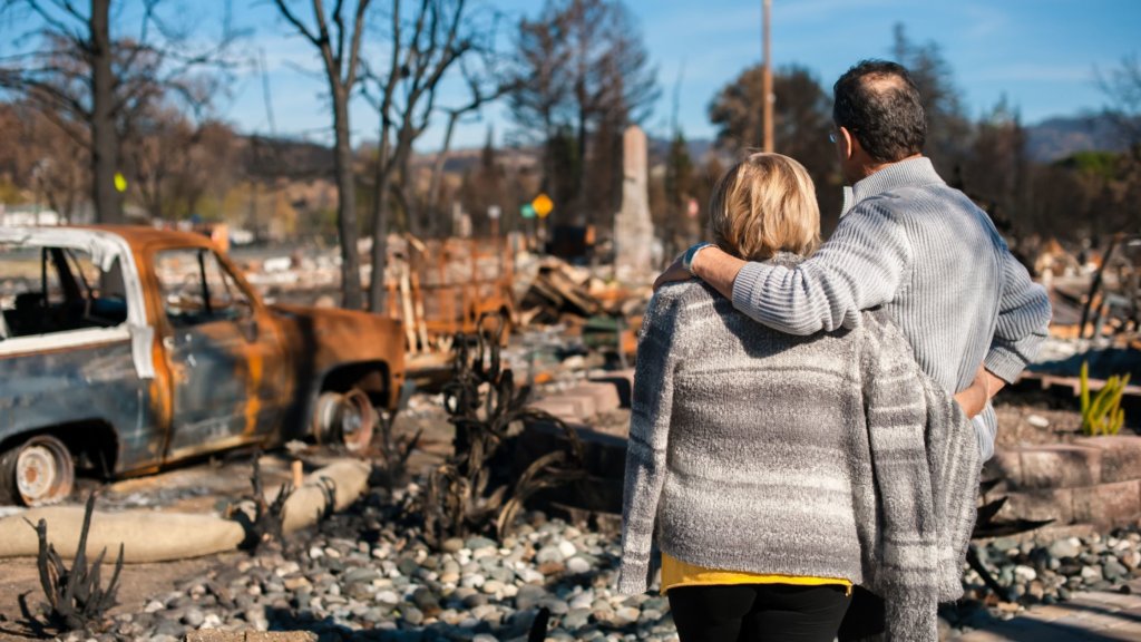 couple looking at rubble of neighborhood after a disaster