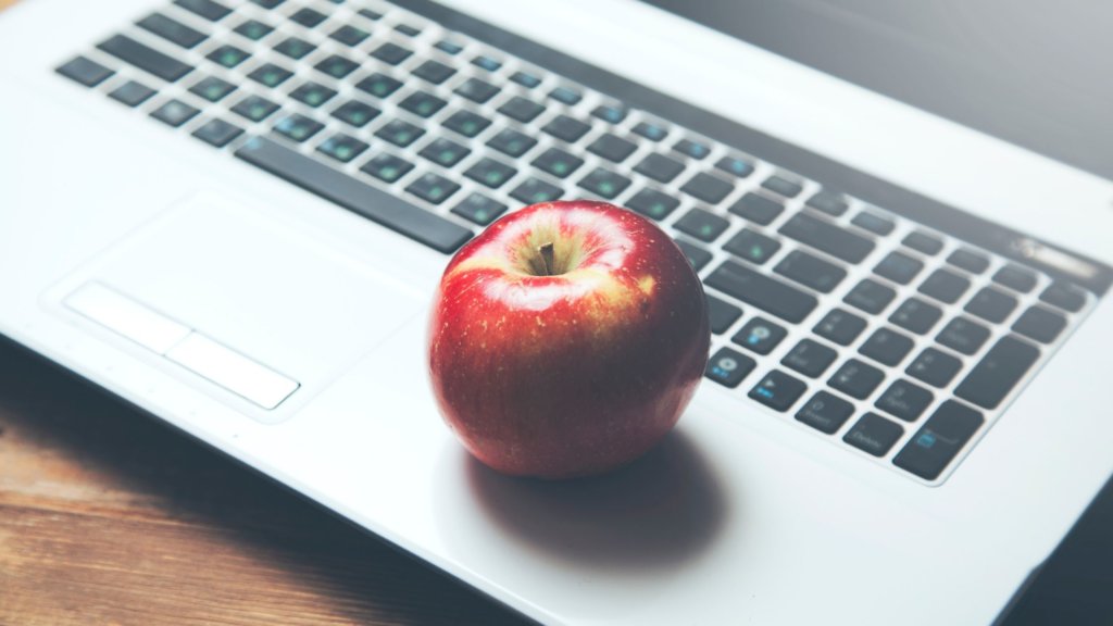 red apple on top of an open laptop computer