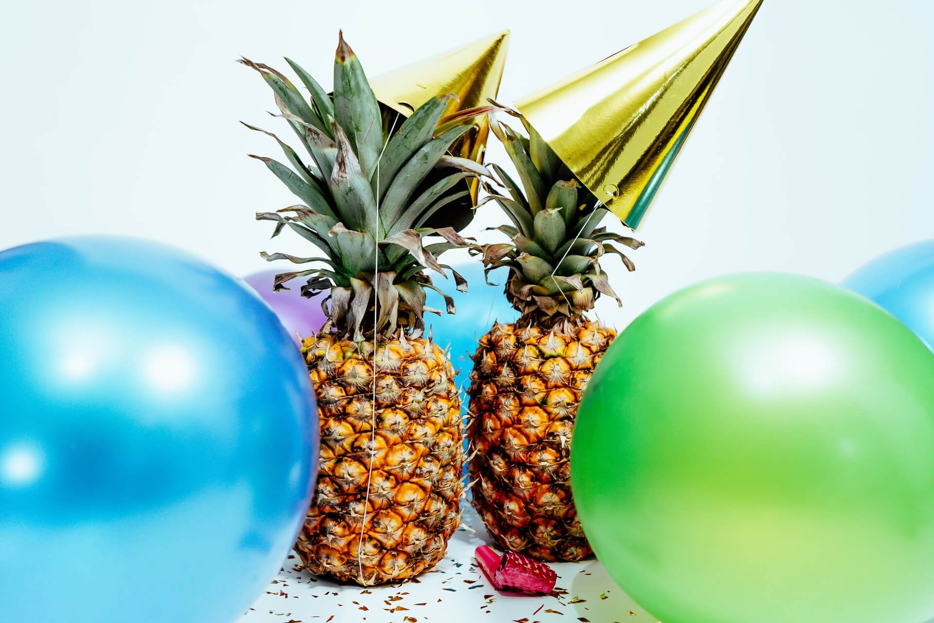 two pineapples with sunglasses and balloons
