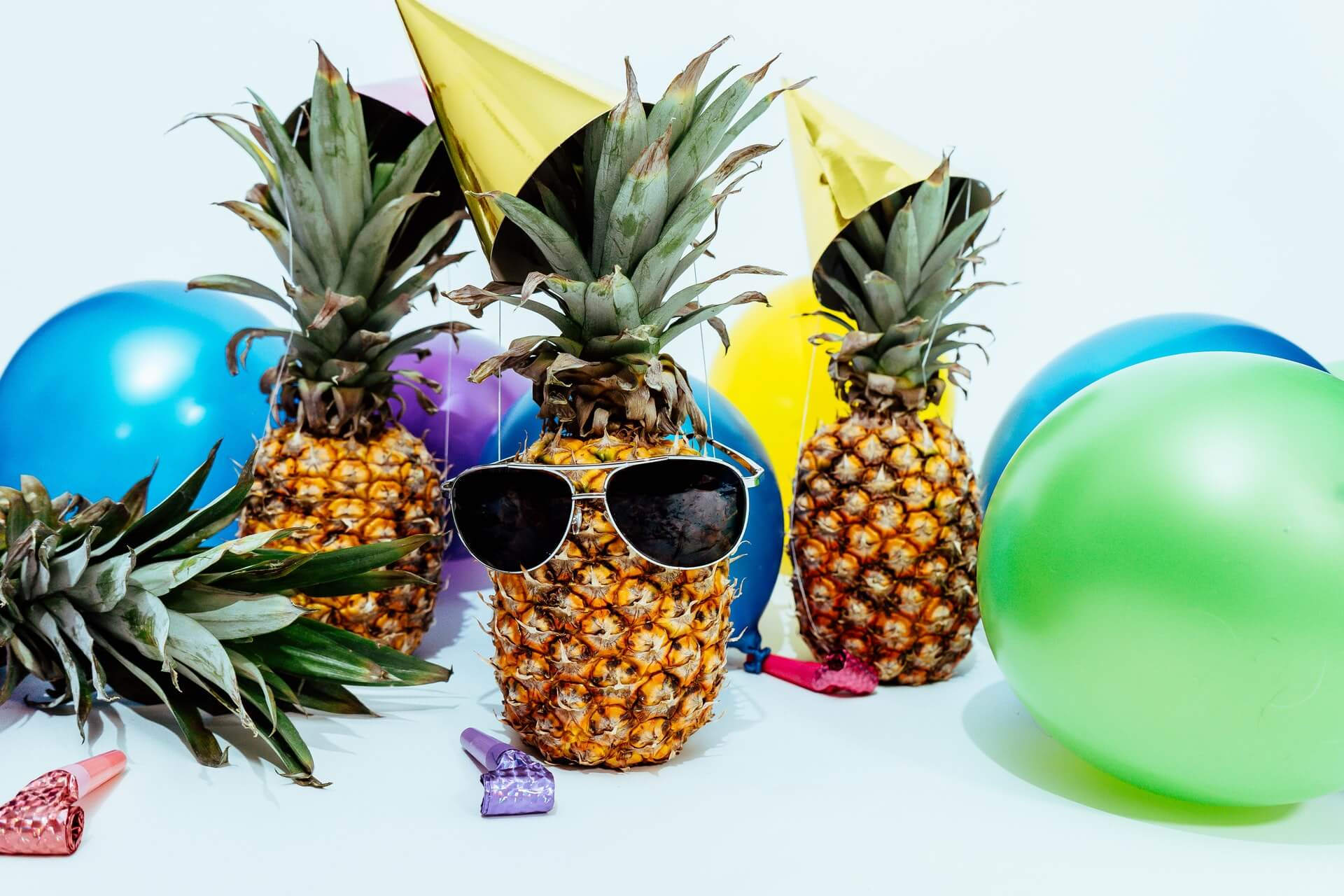 three pineapples with sunglasses and balloons