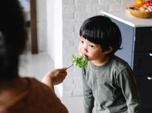 Child eating a leafy green vegetable